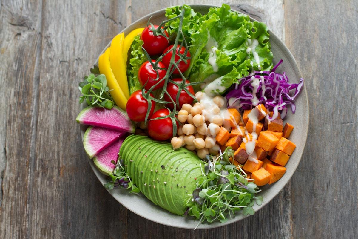 A bowl of salad with tomatoes, grains, and greens